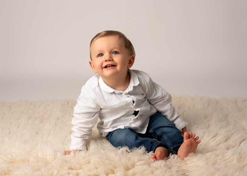 portrait-bebe-studio-landeronde Portrait d’un bébé souriant lors d’une séance photo entre cousins en studio.