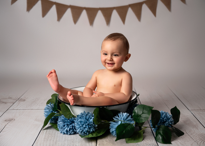 Séance photo bain de lait bébé en studio près des sables d'olonne en vendée. Bébé souriant assis dans une bassine décorée.
