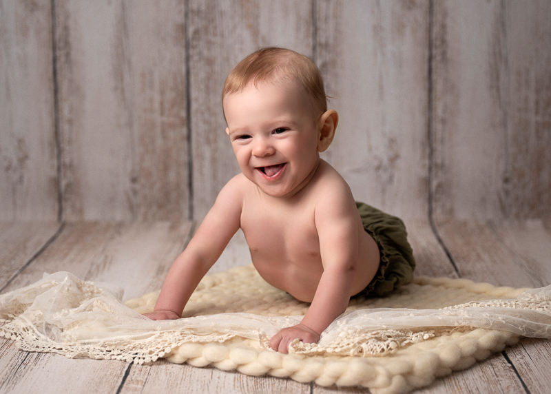Séance photo bébé éveil en studio, bébé souriant et en pleine motricité.