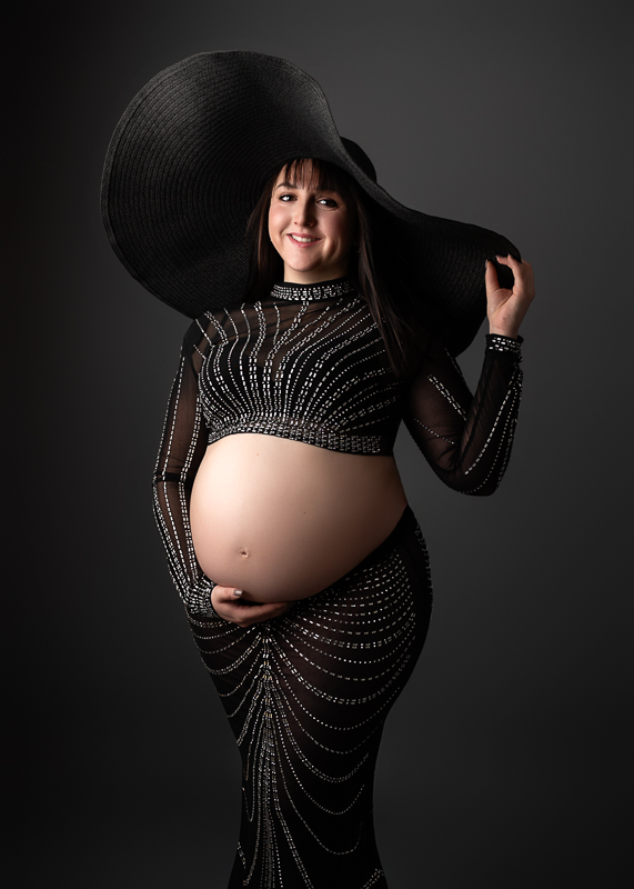 Séance photo grossesse en studio – future maman portant une tenue noire élégante avec chapeau, photographiée à La Roche-sur-Yon en Vendée