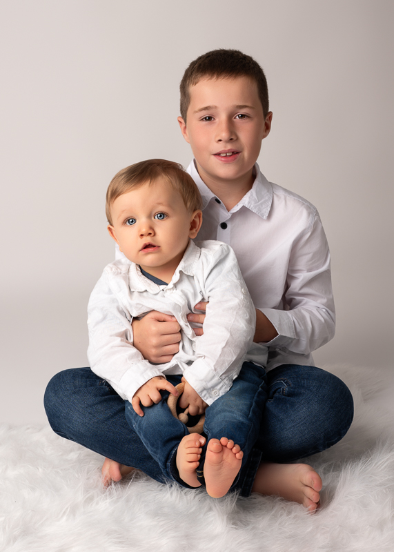seance-photo-cousins-studio-vendee Portrait en studio d’un enfant tenant son cousin bébé lors d’une séance photo familiale.