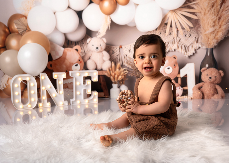 Séance smash the cake bébé en studio avec un joli décor, ballons et guirlandes pour le premier anniversaire de bébé.