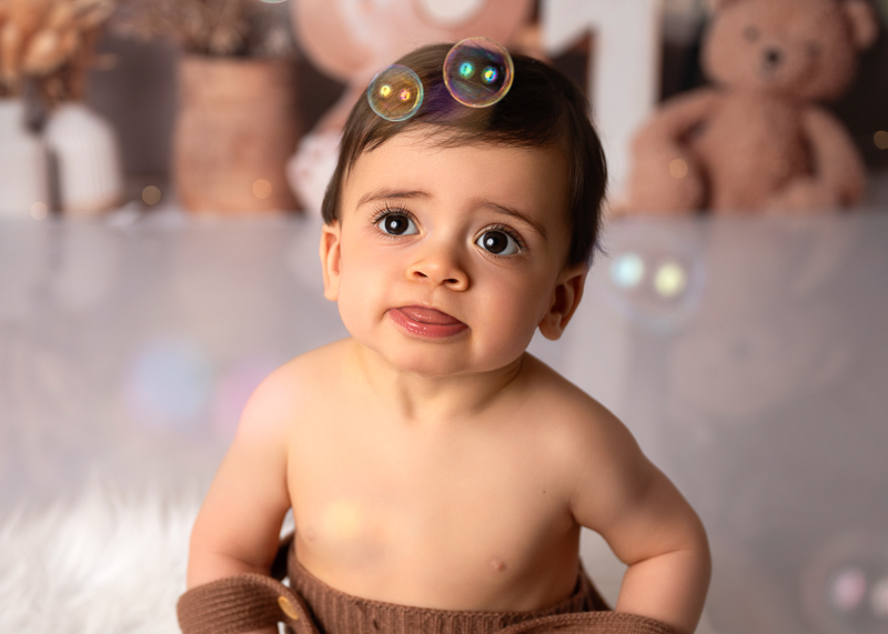 Séance smash the cake bébé en studio, bébé qui découvre les bulles de savon lors de sa séance photo d'anniversaire.