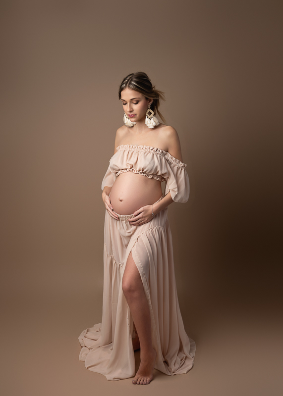 Séance photo grossesse en studio en Vendée, future maman en robe fluide posant avec douceur