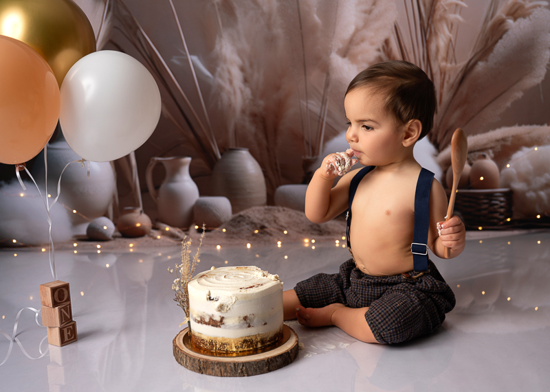 Photo Smash the Cake bébé 1 an découvrant son gâteau d’anniversaire en studio – photographe Vendée