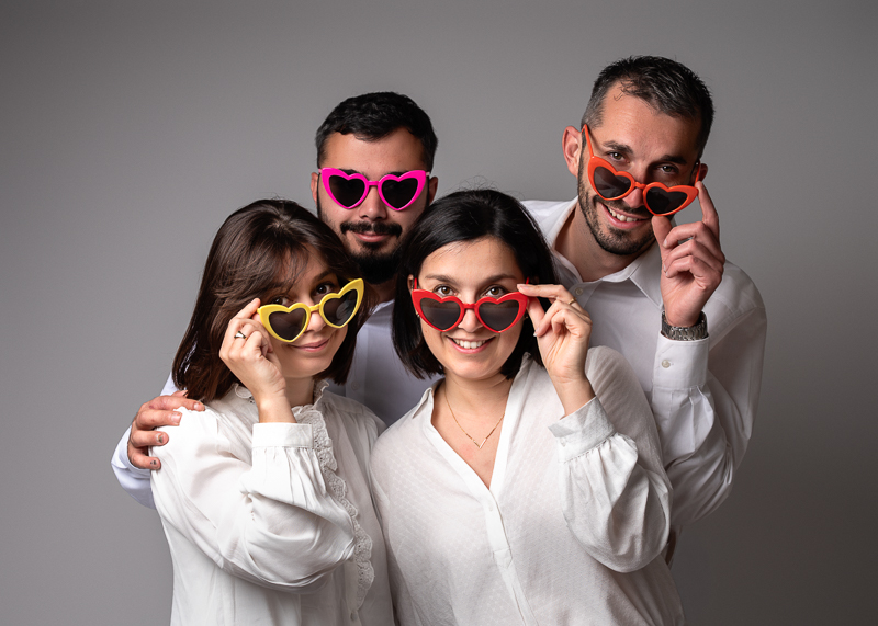 Photo de famille, frères et soeurs, avec lunettes en forme de coeur pour offrir une jolie photo aux parents.