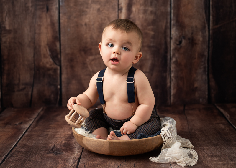 Bébé de 9 mois assis dans un décor bois lors d’une séance photo bébé au studio de Céline Gardé photographe près de La Roche-sur-Yon en Vendée