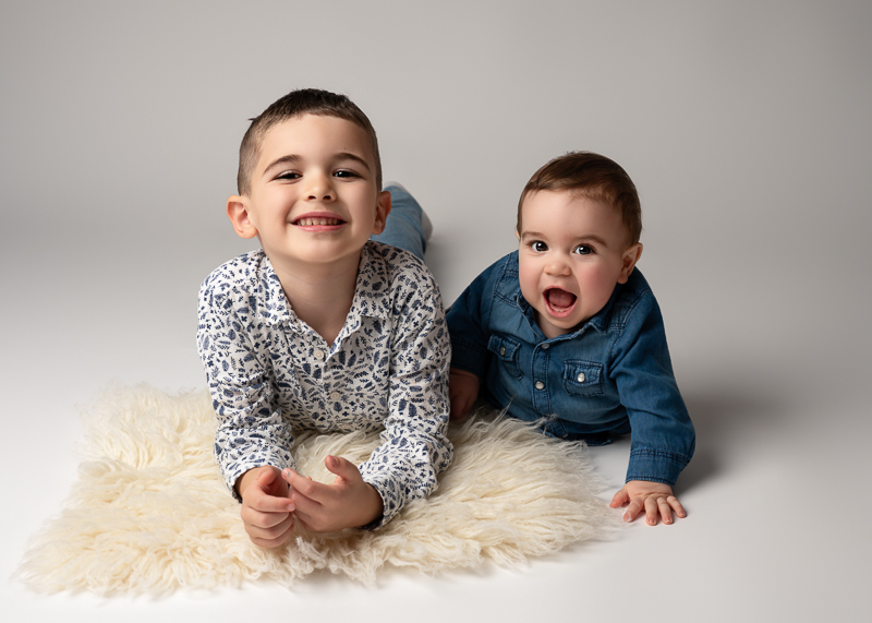 Deux frères allongés sur un tapis lors d’une séance photo enfant en studio près du Poiré-sur-Vie en Vendée.