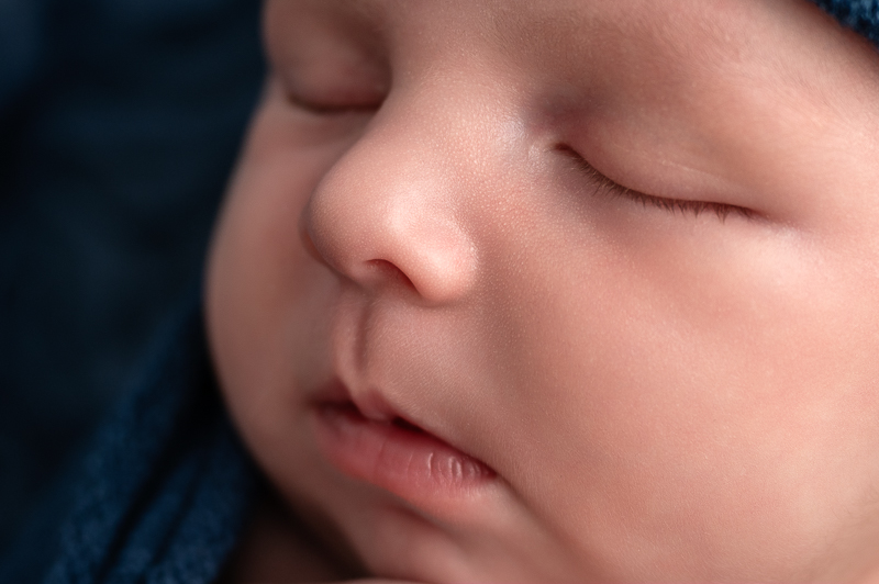 Gros plan sur le visage d'un bébé endormi, détails des cils et des lèvres, séance nouveau-né en studio