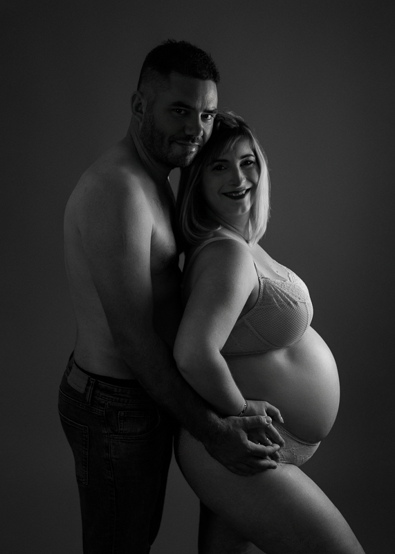 Séance grossesse couple noir et blanc – Studio Vendée Couple enlacé lors d'une séance photo grossesse en noir et blanc, photographe grossesse près de La Roche-sur-Yon