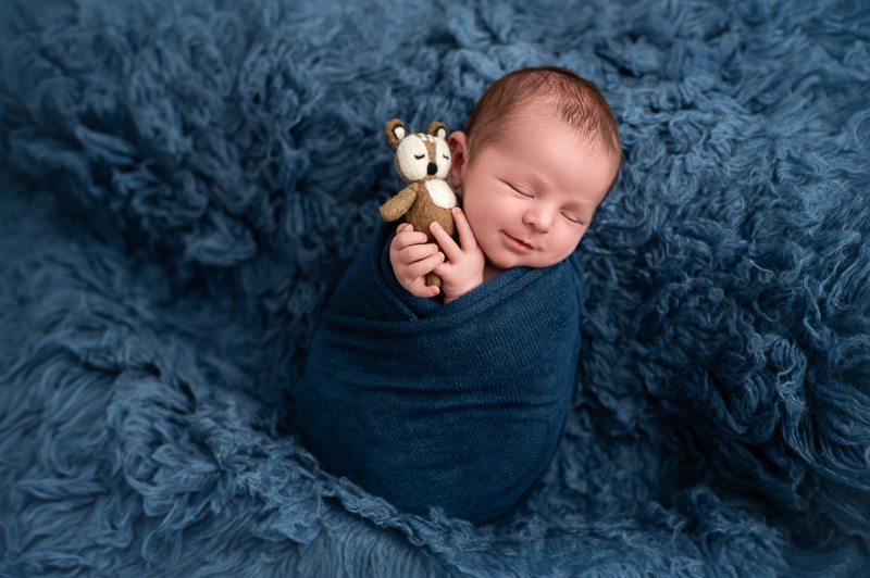 Nouveau-né souriant dans son sommeil avec son doudou renard, photographe bébé en Vendée