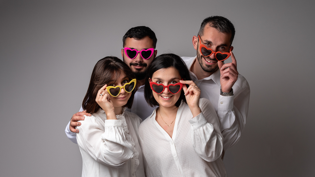 photo de famille réalisée en studio par Céline Gardé, photographe près de la Roche-sur-yon en vendée. Fratrie avec des lunettes de soleil en forme de coeur colorés.
