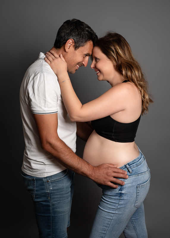 Futurs parents debout, front contre front, qui se sourient, main sur le ventre rond, séance photo grossesse en couple en Vendée